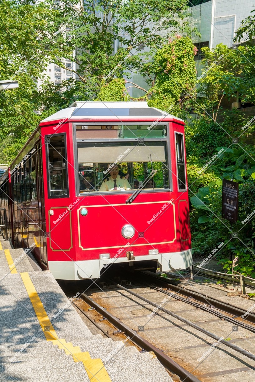Hong Kong island View and a Peak Tram running along the mountain road of Victoria Peak 
Peak Tram heading to the summit