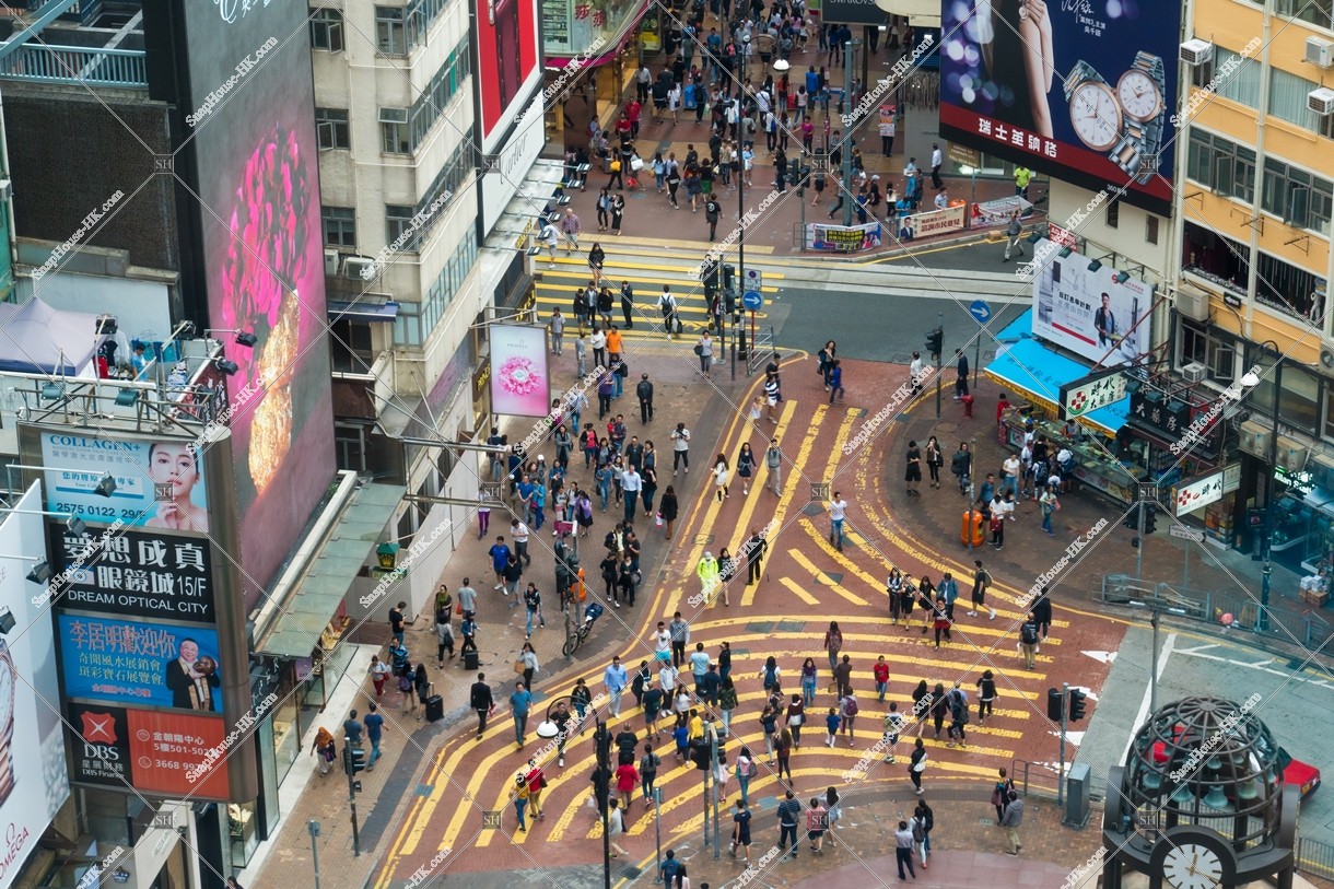 Walkway and crowd of people cross the street in front of Times Square [Portrait]