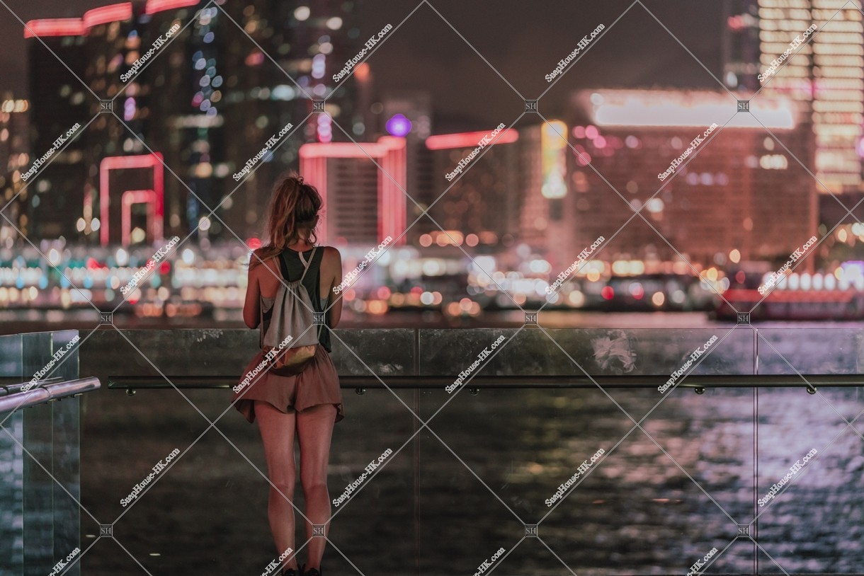A woman with Victoria Harbour at night