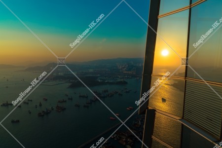 The sunset reflected on the window of SKY 100 and the view of the west side of Hong Kong