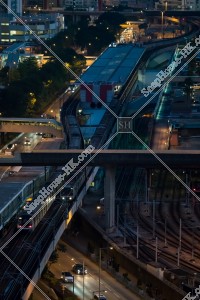 MTR train departing and arriving at Kowloon Bay Station after the sunset